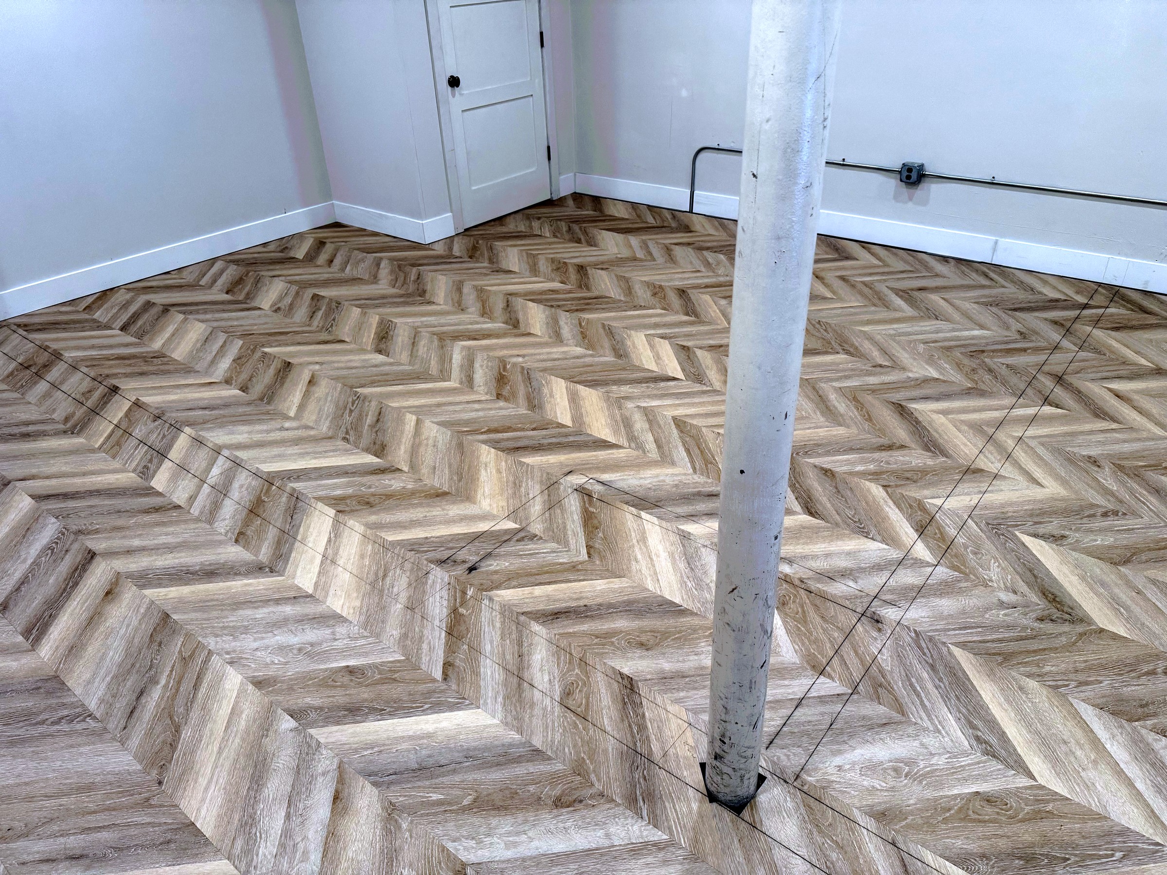 Finished herringbone-style flooring in an open basement area