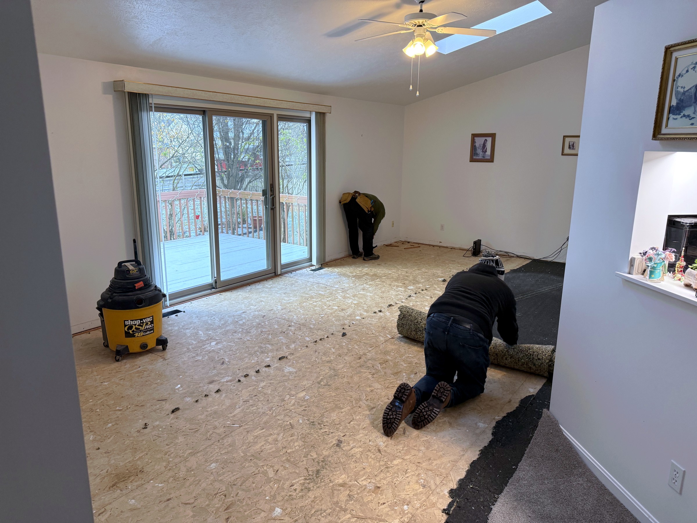 Workers removing old carpet to expose plywood subfloor