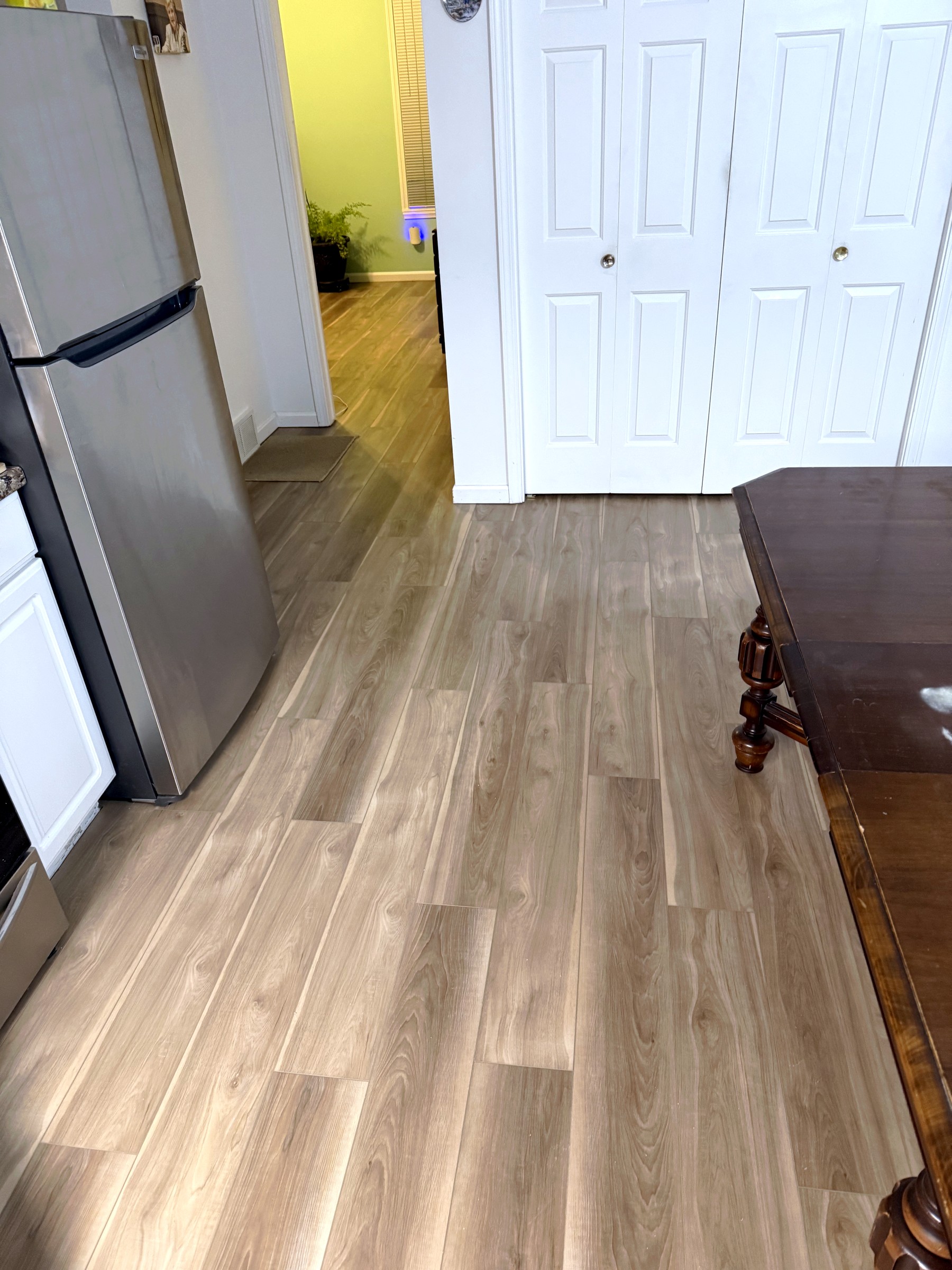 Finished flooring in a kitchen and dining area with stainless steel appliances