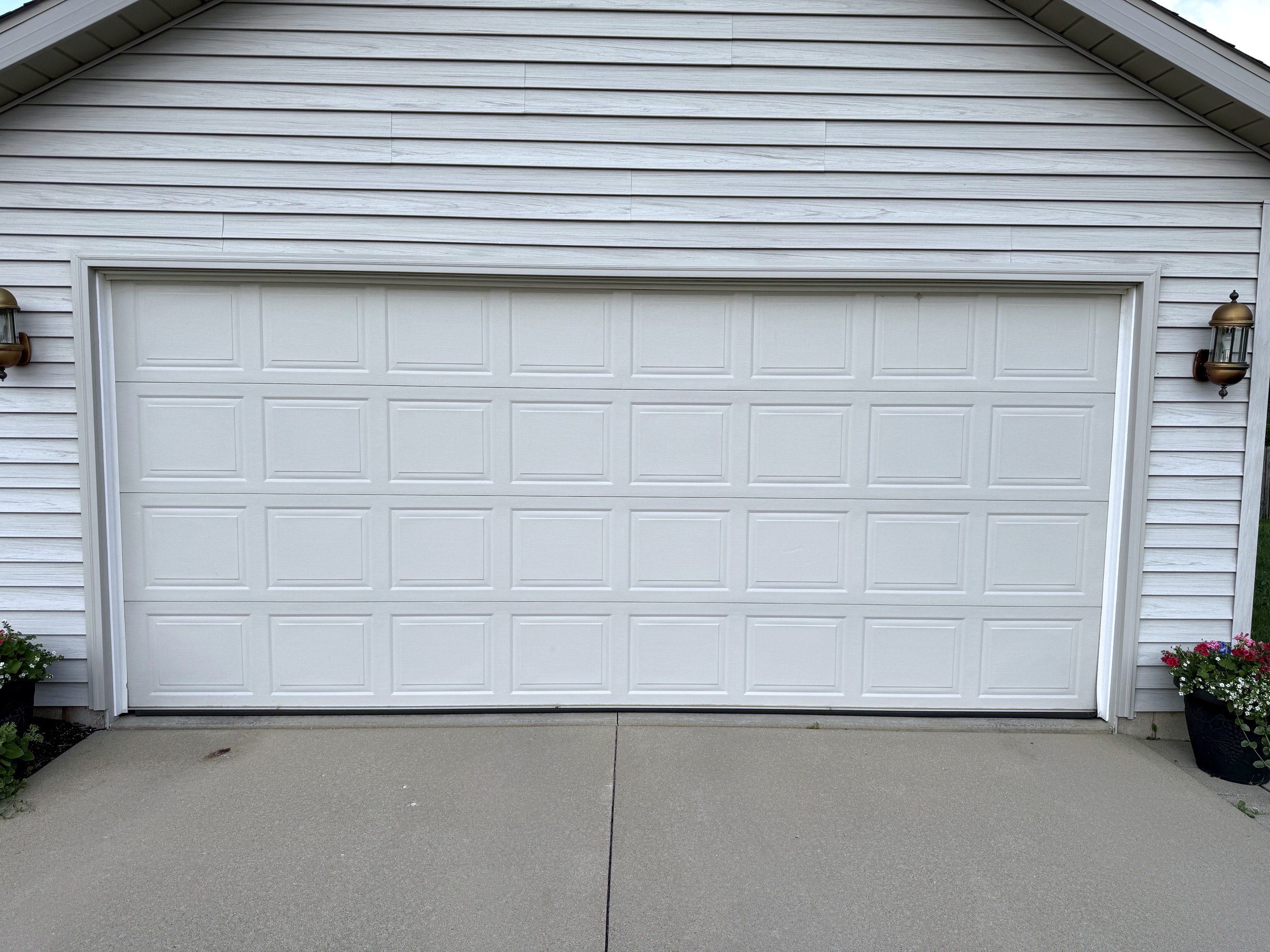 New white multi-panel garage door with exterior sconce lights